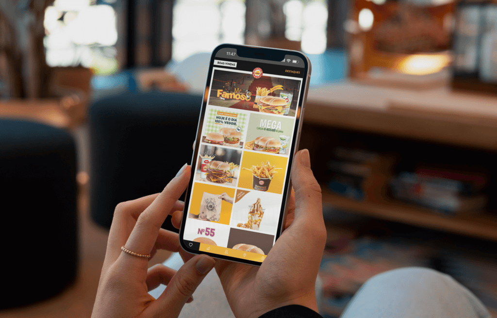 Pessoa segurando o telemóvel com a aplicação do Burger Ranch aberta